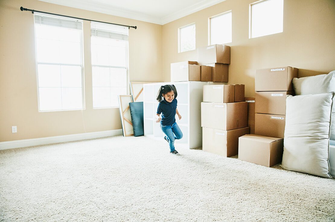 Young girl running in living room filled with boxes on moving day